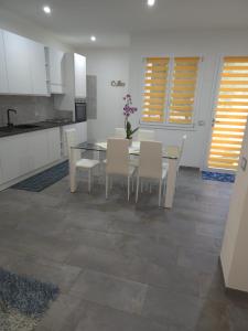 a kitchen with a dining table and white chairs at Le Dune di Quarzo in Càbras
