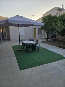 a table and chairs with an umbrella on a lawn at Le Dune di Quarzo in Càbras