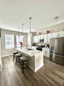 Una cocina con gabinetes blancos y una isla de cocina con taburetes de bar. en Luxury Living Midtown, en Abbeyville