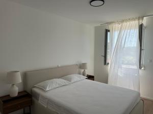 プーラにあるFiorea Apartmentの白いベッドと窓のある寝室