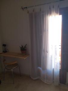 a window with a white curtain next to a table at La Casita Azul in Fuengirola