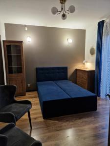 a bedroom with a blue bed and a chair at Granatowy odpoczynek - wieś Pogórze dla zmotoryzowanych in Pogórze