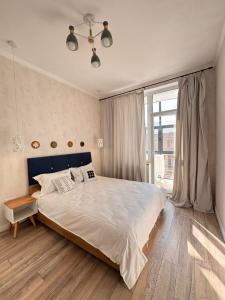 a bedroom with a large bed and a large window at Altin Residens in Karagandy