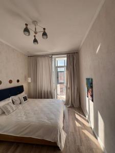 a bedroom with a bed and a large window at Altin Residens in Karagandy