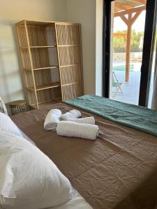 two towels on a bed in a room with a window at Alestone Villa by the sea in Vasilikos