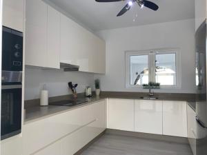 a kitchen with white cabinets and a ceiling fan at Casa Tia, Mojácar with Private Pool and less than 5 minutes from beach! in Mojácar