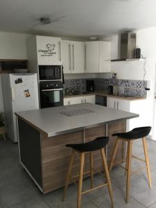 a kitchen with a counter and two bar stools at Le 7ter, maison calme piscine partagée in Saint-Laurent-sur-Sèvre