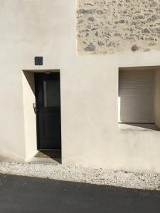 a building with a black door and a window at Le 7ter, maison calme piscine partagée in Saint-Laurent-sur-Sèvre