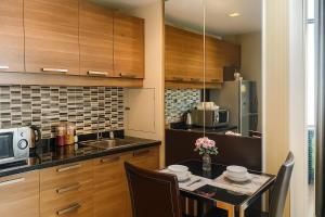une cuisine avec des armoires en bois et une table avec des chaises dans l'établissement Modern 2 Bed Executive Unit - 5min to Nana BTS, à Bangkok