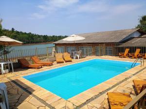 a swimming pool with chairs and umbrellas at Hotel Pousada Icaraí in Poços de Caldas