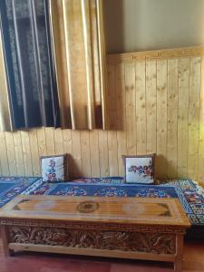 a bed in a room with a wooden table at Life inn Spiti in Kaza