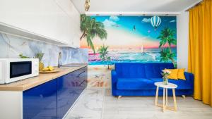 ein Wohnzimmer mit einem blauen Sofa und einem Wandbild am Strand in der Unterkunft Stegna Park II blisko morza Apartamenty Piamola in Stegna