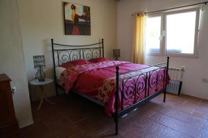 a bedroom with a bed with a red comforter and a window at Ecolodge Carpe Diem El Perelló in Perelló