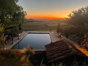 a swimming pool with a sunset in the background at Les 5 terrasses - vue imprenable et piscine privée in La Sauvetat