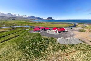 an overhead view of three red barns in a field next to the ocean at Kirkjufell Guesthouse and Apartments in Grundarfjordur