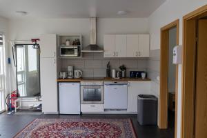 una cucina con elettrodomestici bianchi e un tappeto di Kirkjufell Guesthouse and Apartments a Grundarfjordur