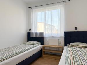 two beds in a small room with a window at Chatka Morska 3 Apartamenty in Karwia