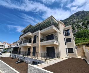 a large white building with a balcony and a mountain at Zen Studio Apartman in Kotor