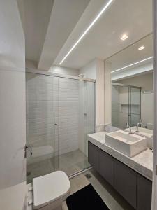 une salle de bain avec toilettes, lavabo et miroir dans l'établissement ID Vida Urbana by Espaço Prime, à Goiânia