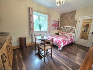 ein Schlafzimmer mit einem Bett und einem Tisch und einem Fenster in der Unterkunft Bluebell Cottage in Armagh