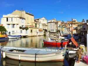 a group of boats docked in a canal with buildings at Camping Pascalounet in La Couronne