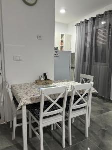 a dining room table with four white chairs and a table and chairsuggest at Apartman 2 in Šušanj