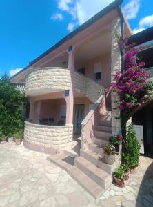 a house with stairs and flowers in front of it at Apartmani Ruža in Vir