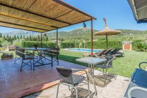 een terras met een tafel en stoelen en een zwembad bij La Rafal in Pollença