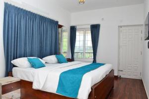 a bedroom with a large bed with blue curtains at Cheerful Chalet in Kodaikānāl