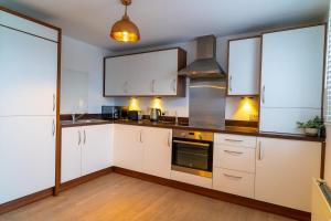 a kitchen with white cabinets and a stove at Two Bedroom En-Suite Modern Apartment Urquhart Road , Beach Area -Free Parking in Aberdeen