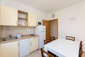 a kitchen with a table and a white refrigerator at Holiday Home Malačnica in Supetar