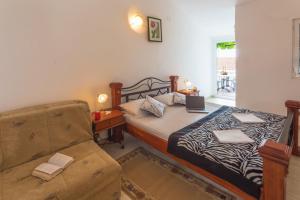 a small bedroom with a bed and a couch at Apartmani Steni in Sveti Stefan
