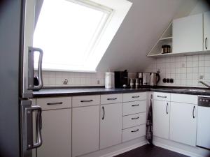 Una cocina con gabinetes blancos y una ventana. en La Domus Premium Osnabrück Lotte, en Lotte