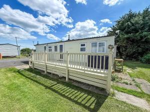 a white house with a fence in the grass at Superb 8 Berth Caravan At Southview Holiday Park Ref 33164Ml in Skegness