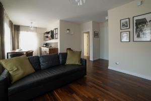 sala de estar con sofá negro y suelo de madera en Dimora Cannavini, en Castel di Sangro