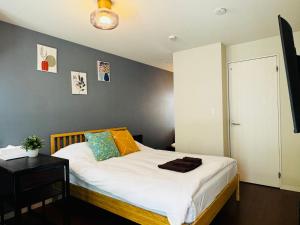 a bedroom with a bed with white sheets and a table at Lucky you! YOTSUYA in Tokyo