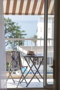 a table and a chair on a balcony at Studio vue mer clim plage aéroport Nice centre commercial centre affaires Nice Arenas emplacement excellent in Saint-Laurent-du-Var