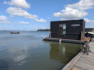 Ein schwarzes Haus auf einem Steg auf einem Wasserkörper in der Unterkunft Winter Getaway Houseboat Stay Romantic in Monnickendam + 6 Fotos