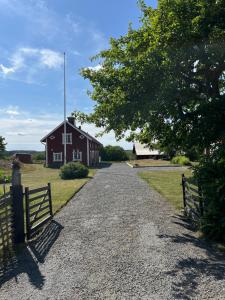 a gravel road leading to a red barn at Vinberga in Enhörna +12 photos