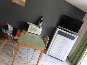 a room with a table and a microwave and a tv at Chez les Petits in Rochefort