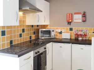 Una cocina con gabinetes blancos y un microondas. en The Cow Shed - Or5, en Henfynyw Upper