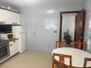 a kitchen with a table and a white refrigerator at Apto Mirandés in Burela de Cabo