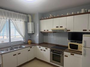 a kitchen with white cabinets and a sink and a microwave at Apto Mirandés in Burela de Cabo