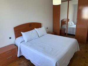a bedroom with a white bed and a mirror at Apto Mirandés in Burela de Cabo +4 photos