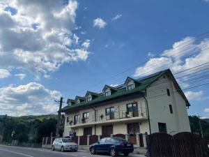 a building with two cars parked in front of it at Casa Anastasia Slănic Moldova in Slănic-Moldova