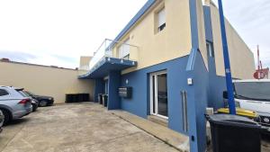 a blue building with cars parked in a parking lot at Appartement T2 avec Balcon, Parking Privée à 2min de la plage, Rue Piétonne in Saint-Jean-de-Monts