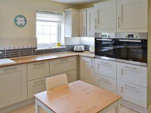 a kitchen with white cabinets and a wooden table at North Shore in Crantock