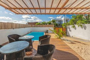 a patio with tables and chairs and a swimming pool at Villa Olive avec piscine privée, proche de la mer in Flic-en-Flac
