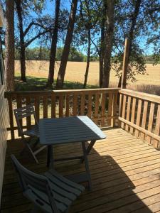 a picnic table and two chairs on a wooden deck at La Rosée du Cardou in Gavaudun