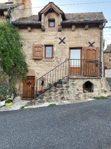 una casa in pietra con una scala di fronte di Petite maison a Les Bondons